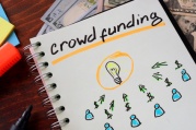 Notebook with crowd funding sign on a table. Start up concept.